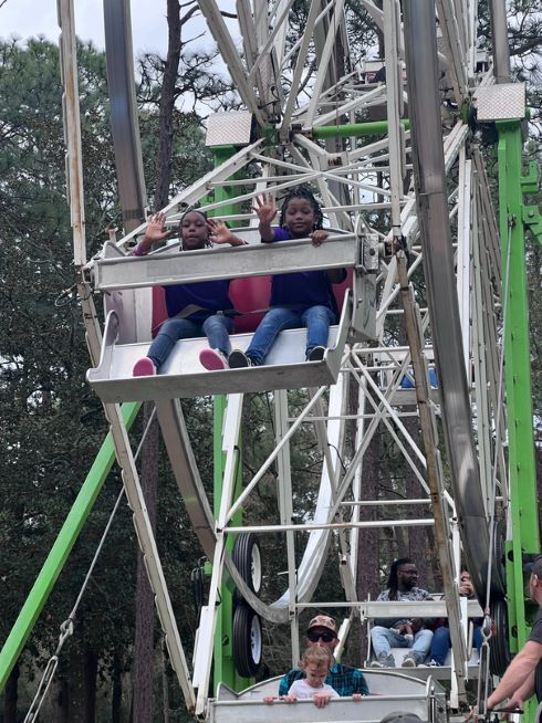 Two children smiling and waving while sitting in a cart on the Ferris Wheel.