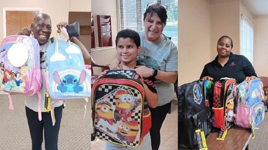 Residents smiling, holding up backpacks. 